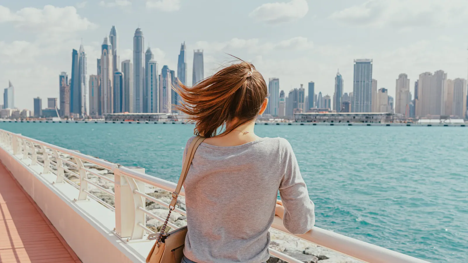 A woman looking out at the Dubai skyline from the waterfront